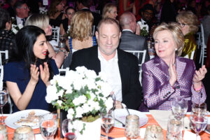 man sitting in a dinner party seated with two women applauding