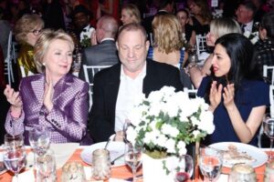 man sitting in a dinner party seated with two women applauding